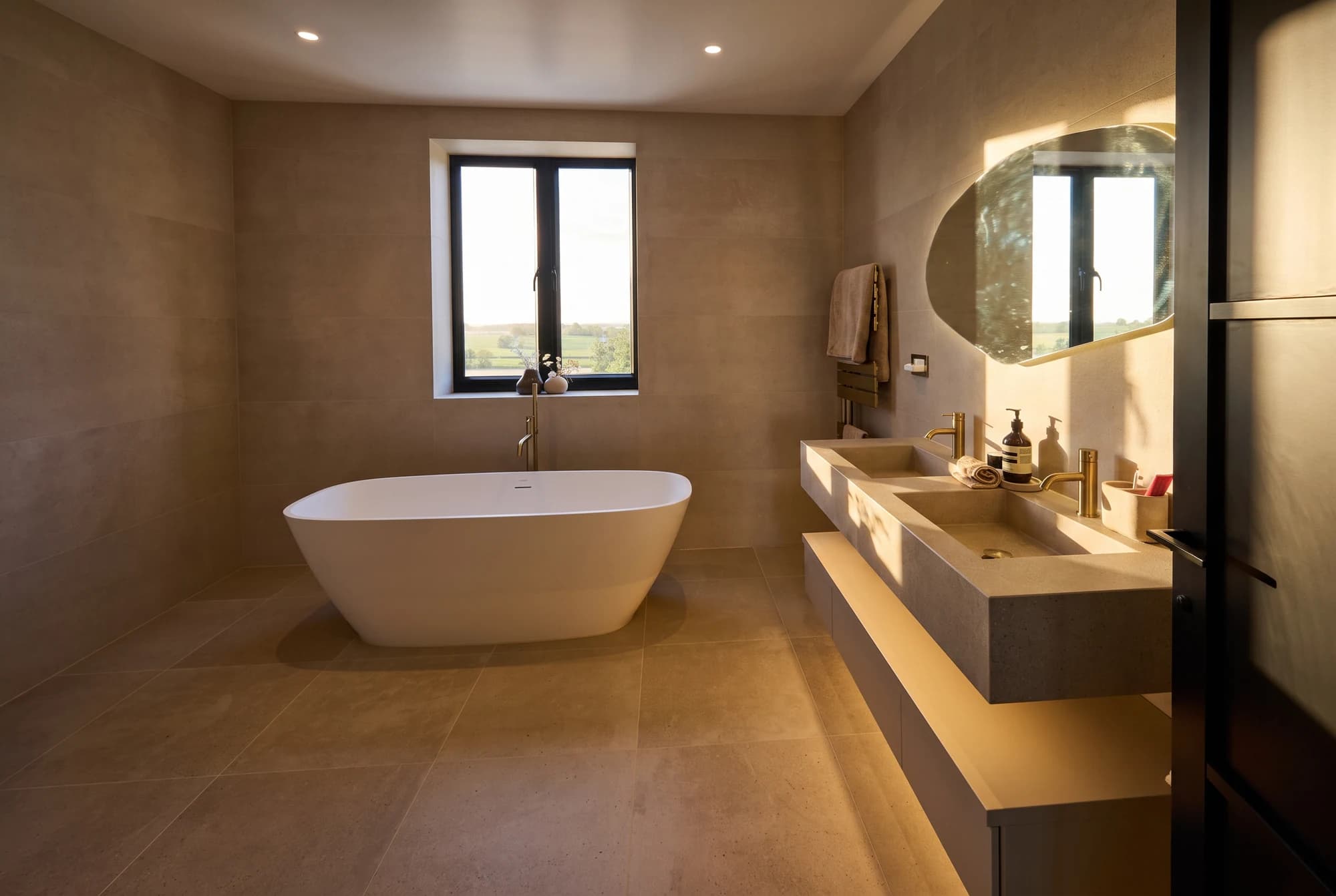 Warm stone bathroom with a freestanding bath and double basin