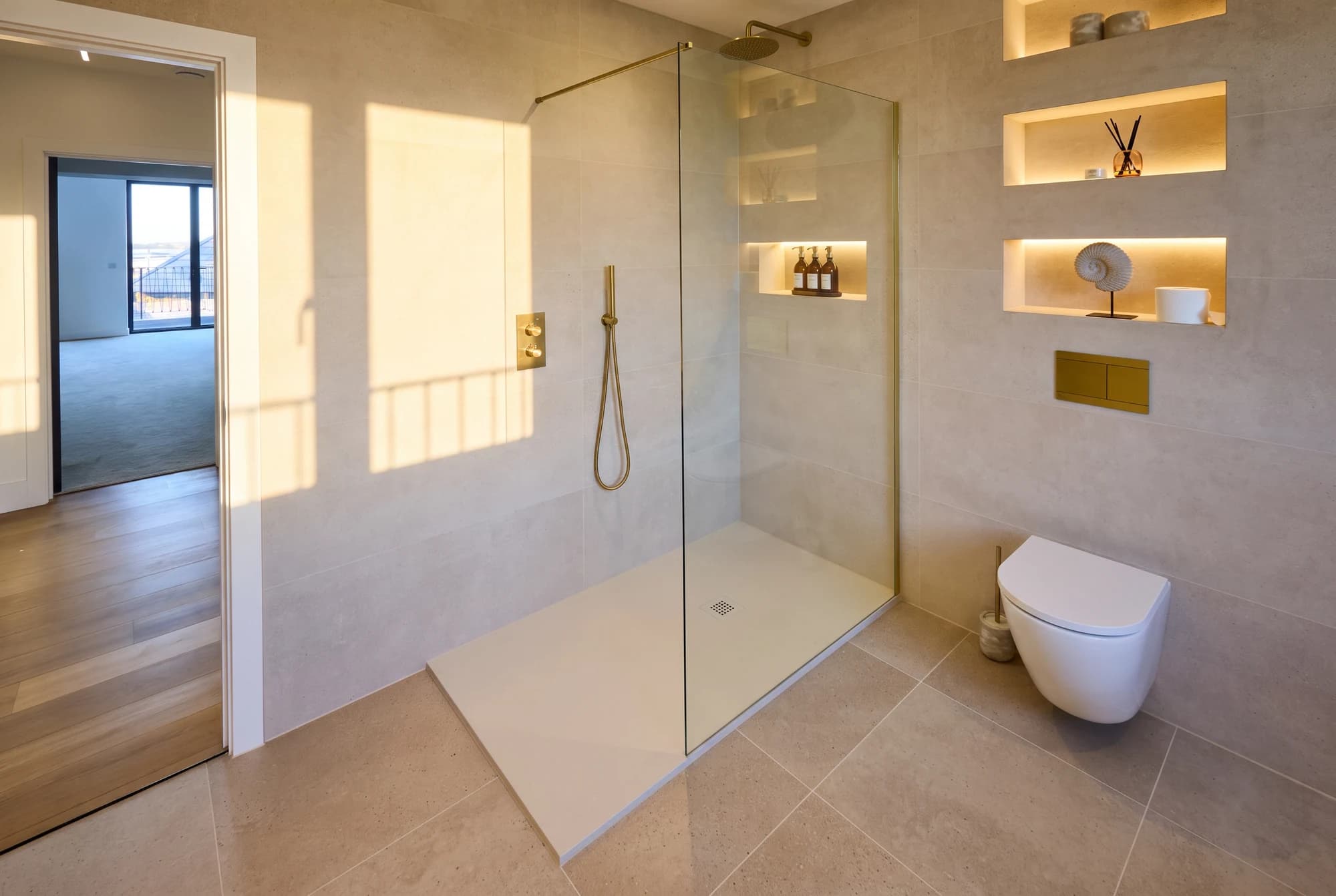 Walk-in shower with brass fittings and illuminated wall niches